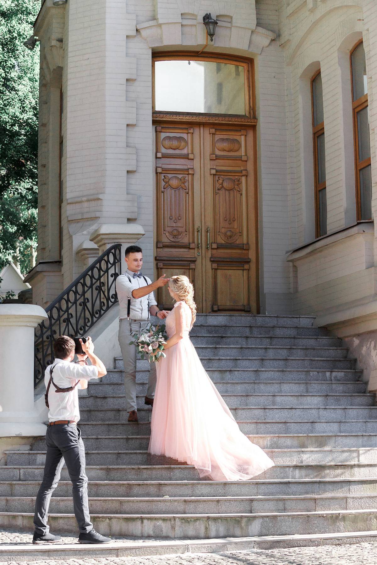 wedding photographer takes pictures of bride and groom in city. wedding couple on photo shoot. photographer in action