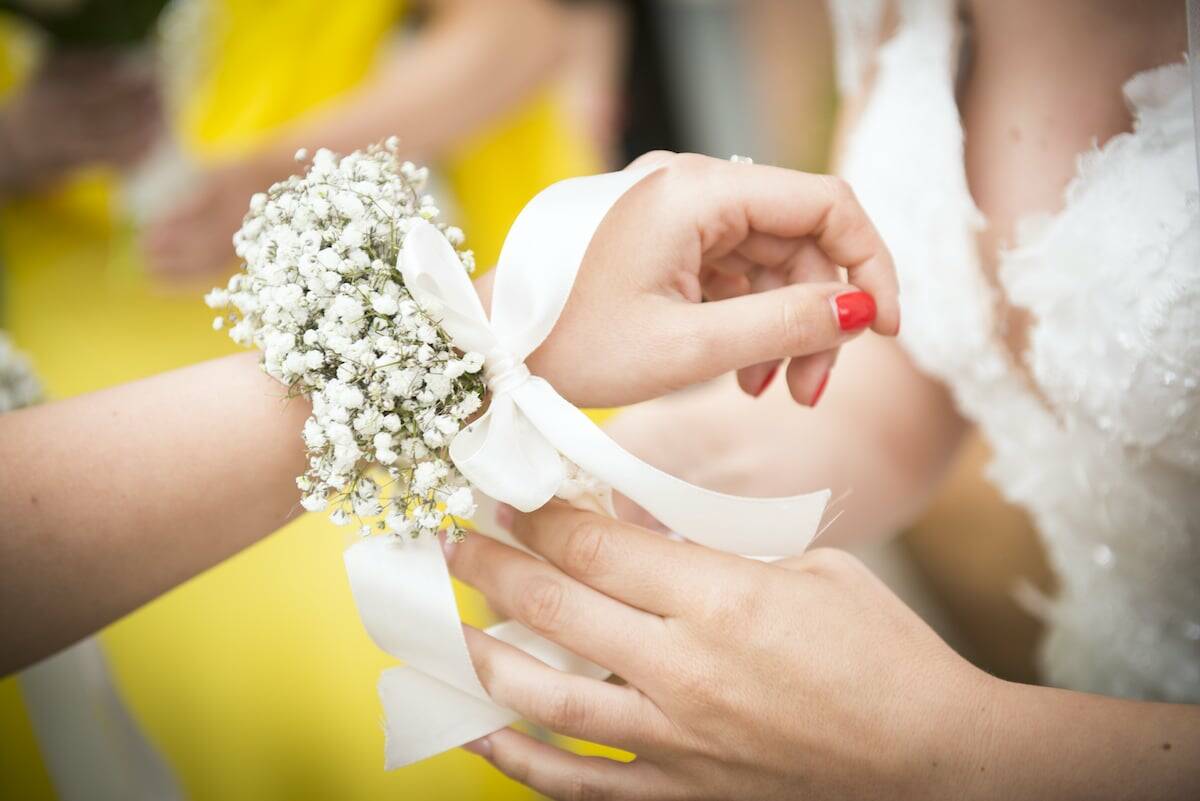bridesmaid is putting flowers on another bridesmaid's wrist