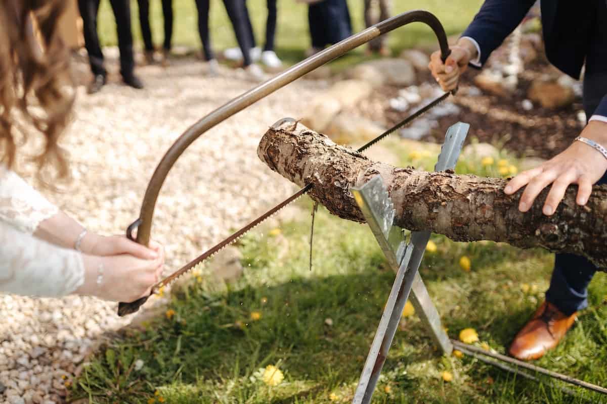 Bride and groom sawing a wooden log as part of a wedding tradition or wedding game