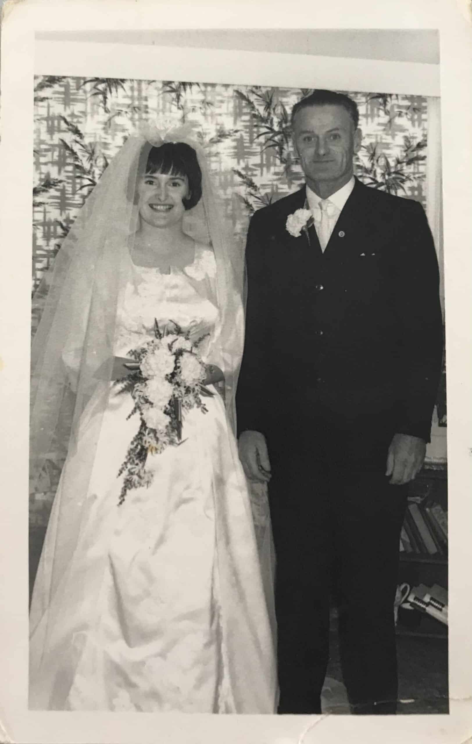 Bride stands with father on wedding day holding a small bouquet 